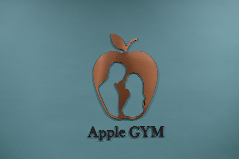Apple GYM（アップルジム）王子店のオリジナルロゴと落ち着く雰囲気の青い壁